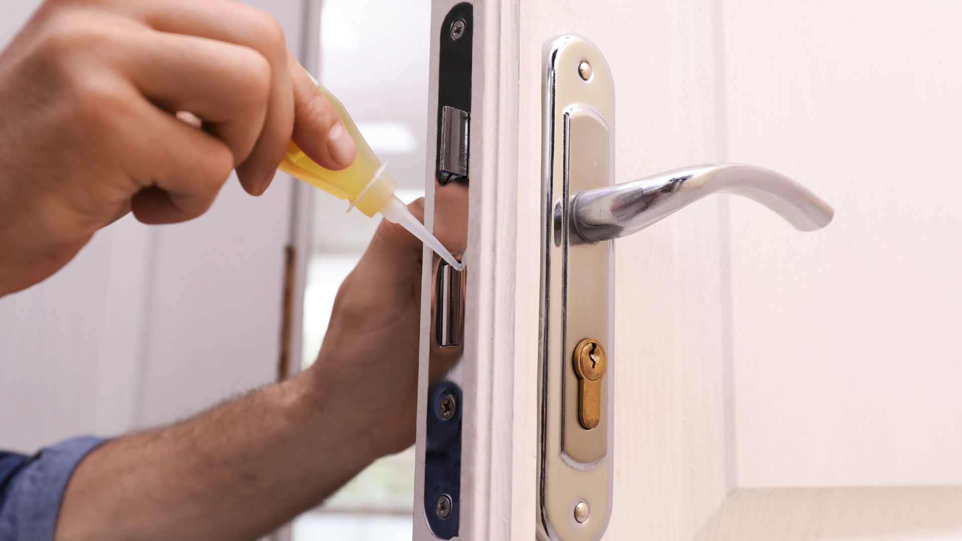 A locksmith using an oil-based lock lubricant on a door lock