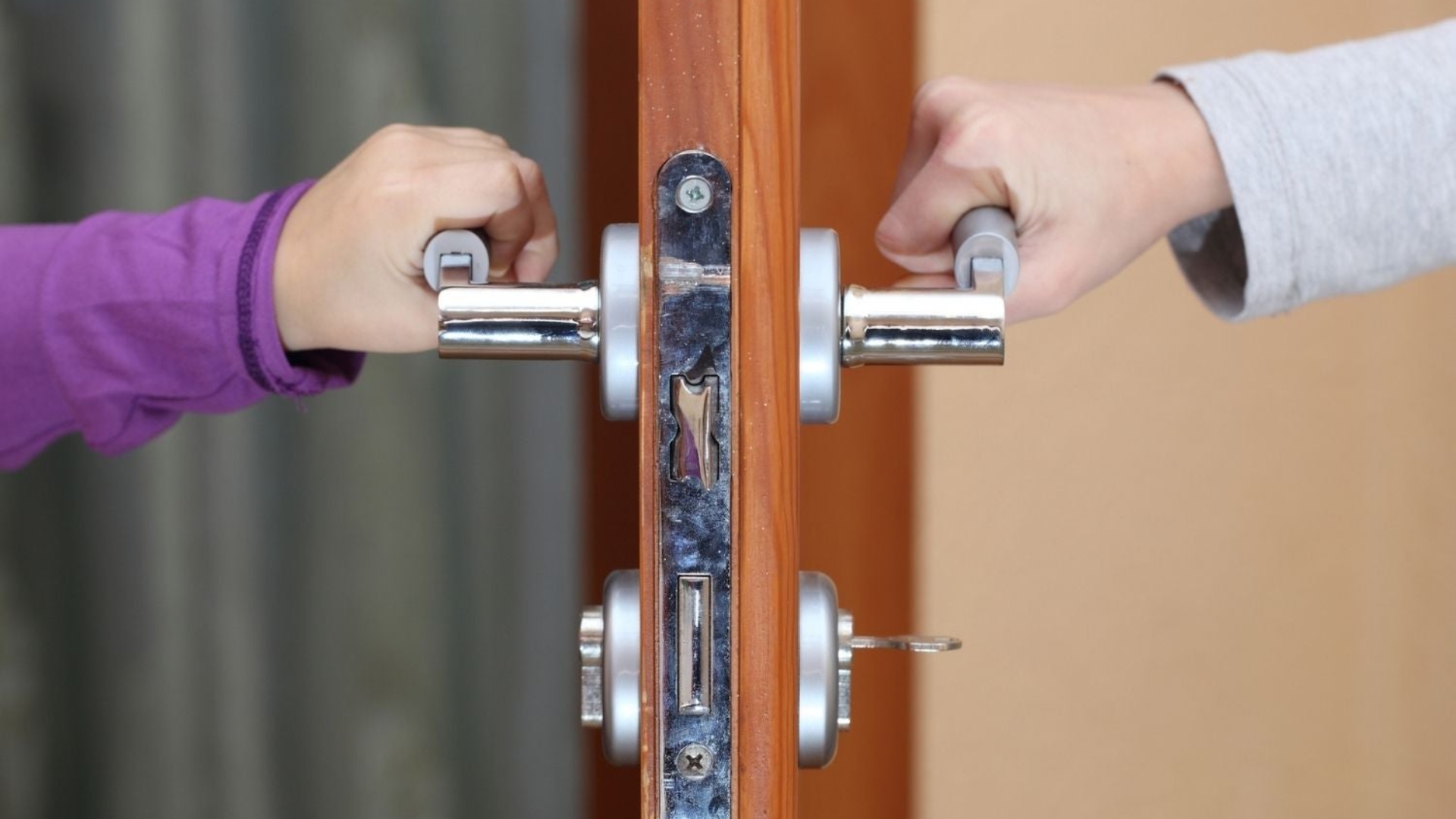 Two users holding a door lever lock on both sides